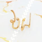 Ατσάλινα σκουλαρίκια Diplo σε χρυσό χρώμα, διακοσμημένα με λευκά στρας.