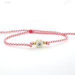 Βραχιόλι - "μαρτάκι" με ανθεκτικό κόκκινο και λευκό πλεγμένο σχοινί. Έχει ατσάλινο στοιχείο κυκλικό στοιχείο με ματάκι, χρυσού χρώματος.